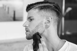 Mann mit 3-Tage-Bart rasiert Bart mit Barttrimmer