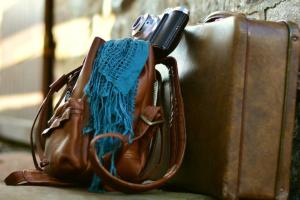 Ledertaschen mit Kamera an Steinwand