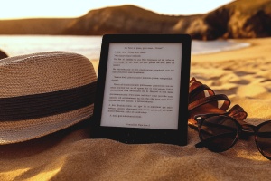 E-Book-Reader an Strand zwischen Sonnenhut und Sonnenbrille